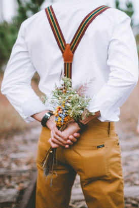 A well dressed man holding a bunch of flowers